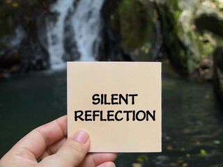 Hand holding paper note with words silent reflection, representing mindfulness, self reflection, mental health, and inner peace concept.
