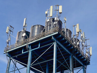 Telecommunication equipment installed on industrial structure with black water storage tank, representing communication infrastructure and utility systems.

