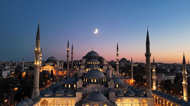 Aerial view of the Blue Mosque in Istanbul, Turkey, illuminated at twilight. Historic Islamic architecture with a crescent moon in the sky. Ramadan and Eid concept