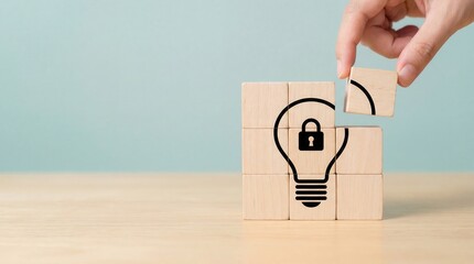 A human hand places the final wooden block completing a lightbulb with a prominent lock symbol representing secure innovation and intellectual property protection on a na