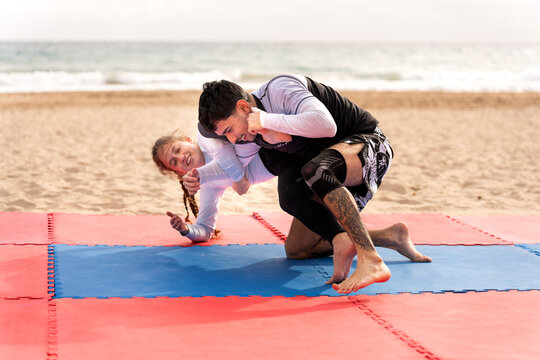 Friends grappling jiu jitsu on beach mat