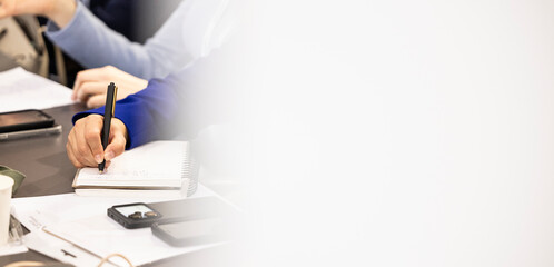 Person's hand writing in a spiral notebook, capturing information during a professional meeting
