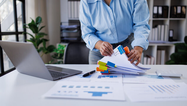Businesswoman hands working in Stacks of paper files for searching and checking unfinished document achieves on folders papers at busy work desk office

