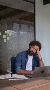 Stressed businessman experiencing burnout and headache at office desk