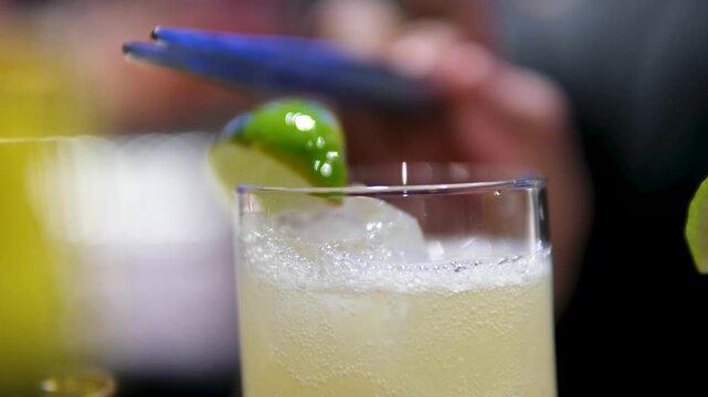 Pouring refreshing alcohol drink with bubbles, ice, lemon lime, gin tonic, soda. Close up shot.