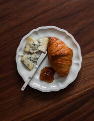 Croissant, fig jam and gorgonzola cheese on a wooden background, top view. Delicious breakfast, snack, dessert