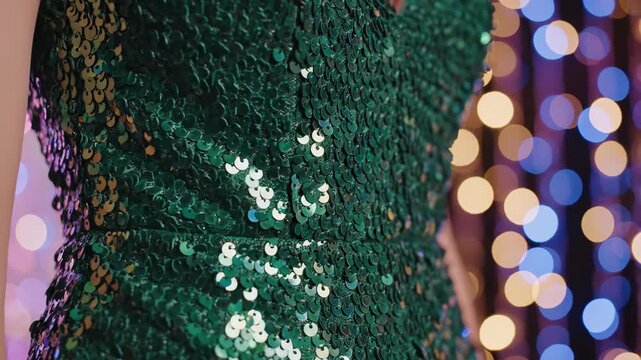 Close-up of shimmering emerald green sequin dress texture. Woman wearing festive party outfit with bokeh lights for St. Patrick's Day