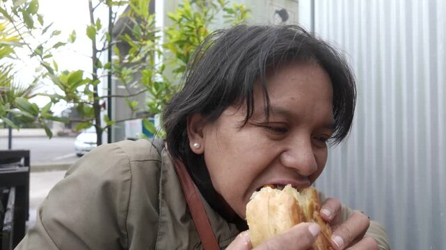 A woman enjoys eating a New Zealand meat pie, with a visible bite revealing the savory filling, capturing comfort food, local cuisine, and a satisfying eating moment.