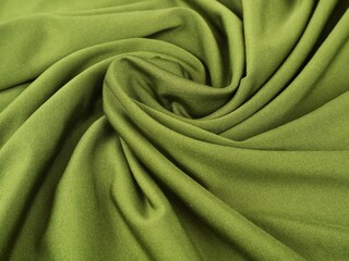 Close-up of olive green fabric with soft swirling folds. Perfect for themes related to fashion, garment manufacturing, and textile background
