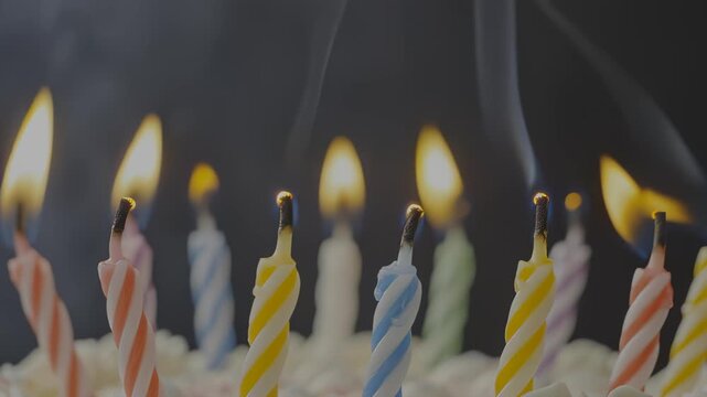 Colorful birthday candles burning brightly on a cake, flames flickering, smoke rising as the candles begin to extinguish, showcasing the celebration's joyful moment and transition
