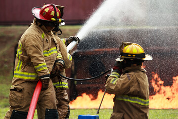 Obraz premium Firefighters spraying water to control fire during emergency training