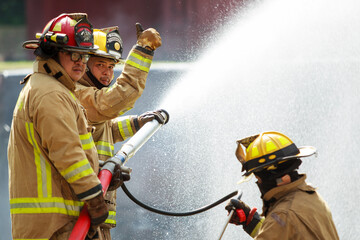 Fototapeta premium Firefighters spraying water to control fire during emergency training