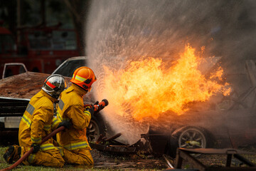 Naklejka premium Firefighters extinguishing burning car during emergency response
