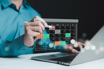 Business professional selecting date on digital calendar with stylus pen and laptop, representing...