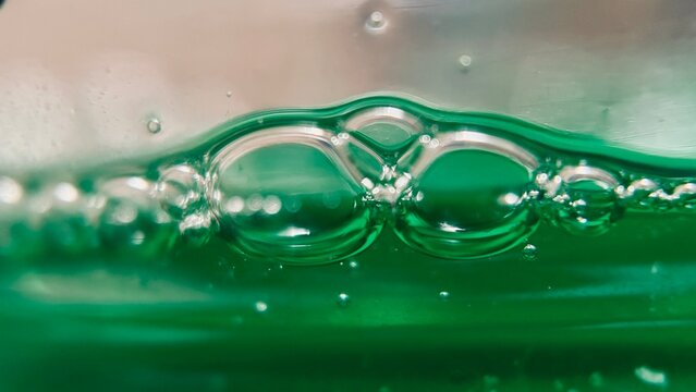 Macro close-up of bubbles formed on green liquid dishwashing soap.