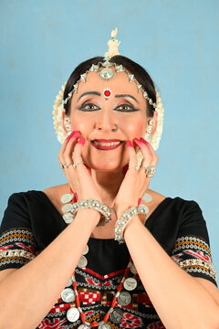 An Indian dancer girl poses in a dance pose in a studio on a blue background