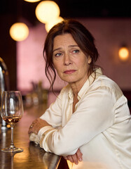 Lonely sad woman sitting at bar with glass of wine