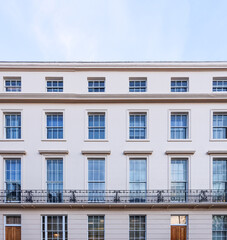 Obraz premium Traditional Georgian architecture facade with rows of classic white windows and a wrought iron balcony in London