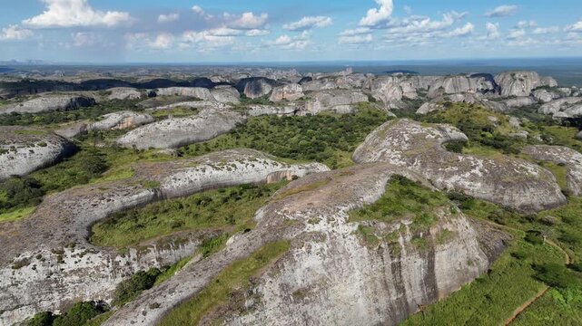 Cinematic birds-eye view of the volcanic rock towers and lush tropical vegetation of the Pungo Andongo region Wide panoramic drone overview of the Pedras Negras rock formations