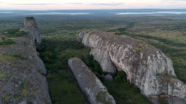 Aerial drone flight inside the deep stone fissures of Pedras Negras de Pungo Andongo in Malanje Province, Angola, Africa, showing massive vertical cliffs at sunset