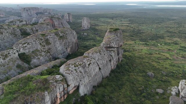 Cinematic flight over the ancient stone giants of Pedras Negras, Pungo Andongo, Malanje, Angola, Africa, rising from the tropical greenery