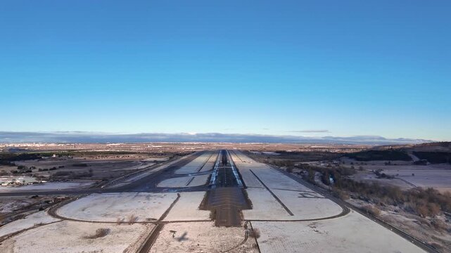 Unique Pilot&rsquo;s perspective taken from inside a jet airplane cockpit in a real time landing to Madrid airpor after a rare winter snowfall, under a blue sky, with the shadow of the airplane on the groun