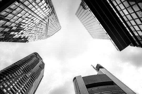 Monochrome modern urban skyscraper tower architecture with upward perspective lines reaching into sky creating dramatic minimal highrise view