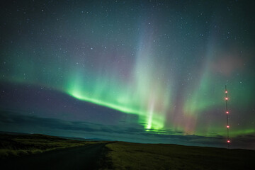 View of the vibrant aurora borealis dances across the night sky, painting the Icelandic landscape with ethereal green and purple hues, Grundarfjordur, Iceland.