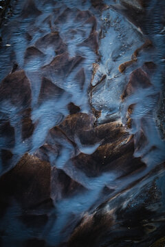 View of an otherworldly landscape with dark, textured earth crisscrossed by veins of pale blue mineral deposits, creating a mesmerizing pattern, Rejkjahlid, North Iceland, Iceland.