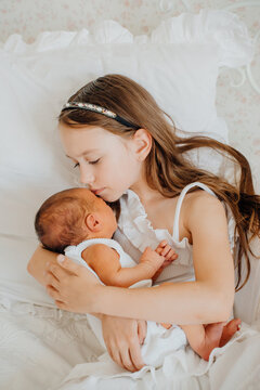 Sister holds newborn baby in quiet moment at home