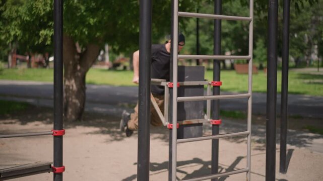 White Man Training On Outdoor Bars, Steady Rhythm And Focused Posture As He Navigates Metal Ladder And Parallel Bars, Summer Park Backdrop, Casual Athletic Clothing And Cap, Deliberate Grip