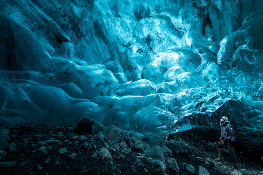 View of an explorer dwarfed by the ethereal blue ice formations in the Sapphire Ice Cave, a frozen cathedral of nature, Vatnajokull glacier, Iceland.