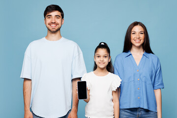 Young happy parent mom dad with child kid daughter girl wear casual clothes hold in hand use blank...