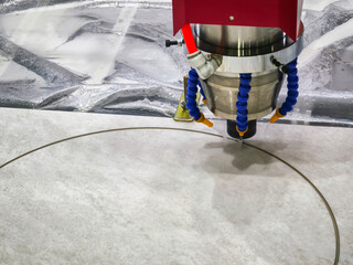 Water jet cutting machine working on a circular design on a stone surface in a workshop