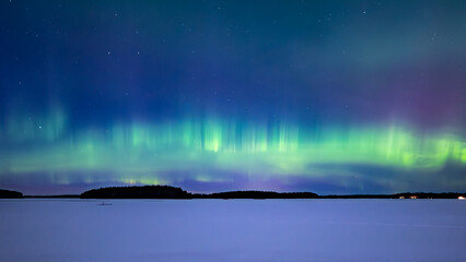 Northern lights dancing over frozen lake in north of Sweden.