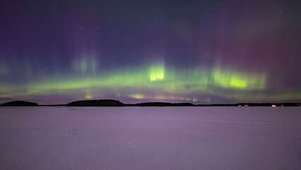 Northern lights dancing over frozen lake in north of Sweden.