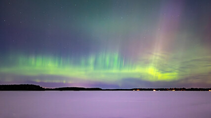 Northern lights dancing over frozen lake in north of Sweden.