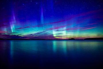 Northern lights dancing over calm lake in north of Sweden.