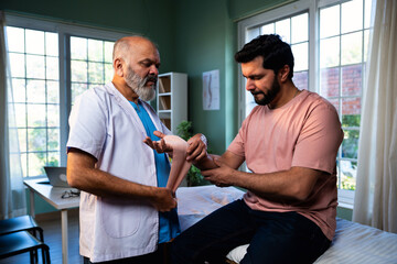 Indian physiotherapist treating wrist pain by applying support band to male patient