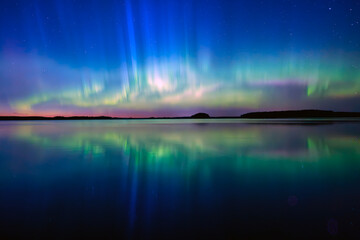 Northern lights dancing over calm lake in north of Sweden.