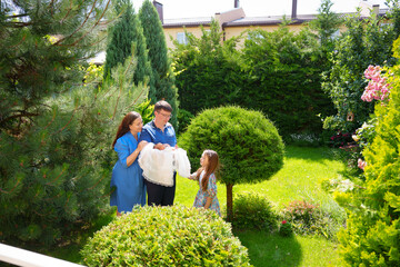 Family enjoys time in garden with child and new baby