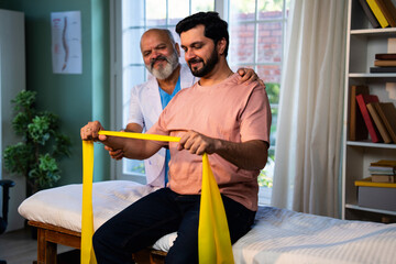 Indian physiotherapist teaching patient resistance band exercises for shoulder strength training