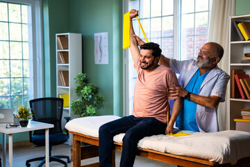 Indian physiotherapist teaching patient resistance band exercises for shoulder strength training