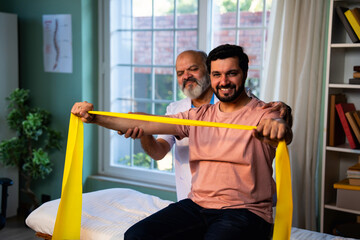 Indian physiotherapist teaching patient resistance band exercises for shoulder strength training