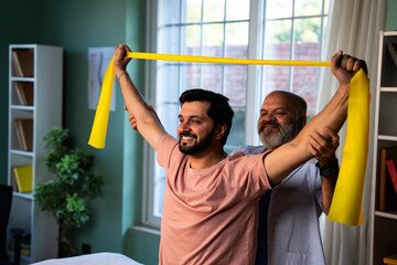 Indian physiotherapist teaching patient resistance band exercises for shoulder strength training