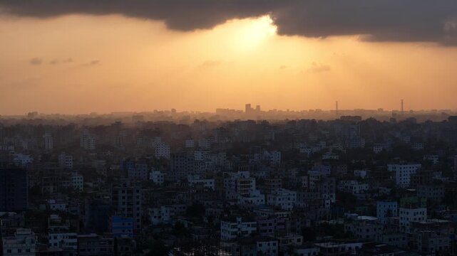 Dramatic Dhaka cityscape at sunset with sunbeam through clouds