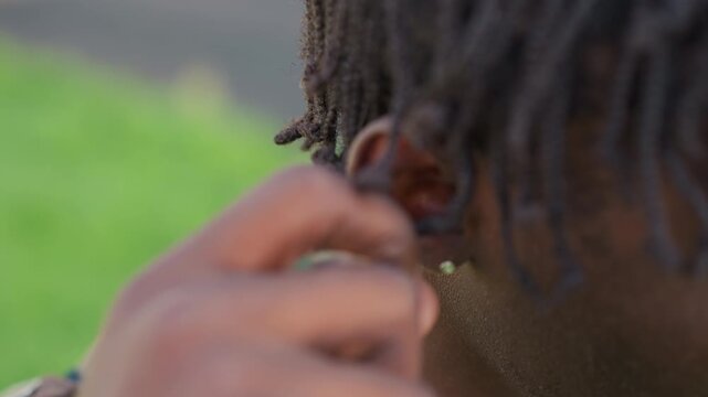 Black Soldier Tucking Dreadlock Behind Ear, Focused Expression And Careful Fingers In Green Park Subtle Gesture Prepares For Listening And Conversation, Conveying Attention, Calm And Personal Care