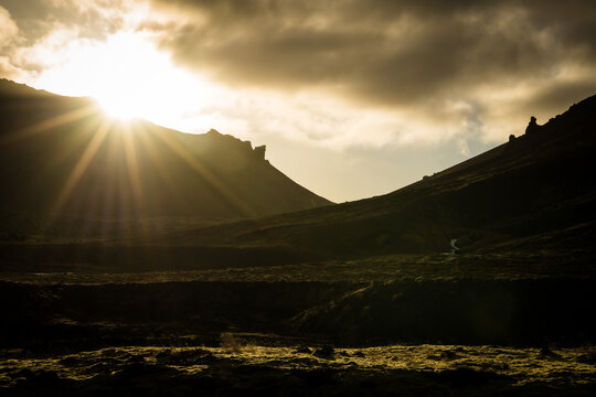 View of the sun bursting through the clouds over the dark, rugged terrain of the Snaefellsnes Peninsula, a mystical landscape, Grundarfjordur, West Iceland, Iceland.