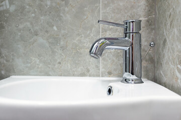 Luxury hotel clean design chrome bathroom faucet close up.