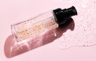 Fluid cosmetic product 24k gold gel in a glass bottle on pink background. Beauty serum, peptides, essence, wellness ads, cosmetic presentations. Skin care, face cream, mask, body lotion, moisturizer 